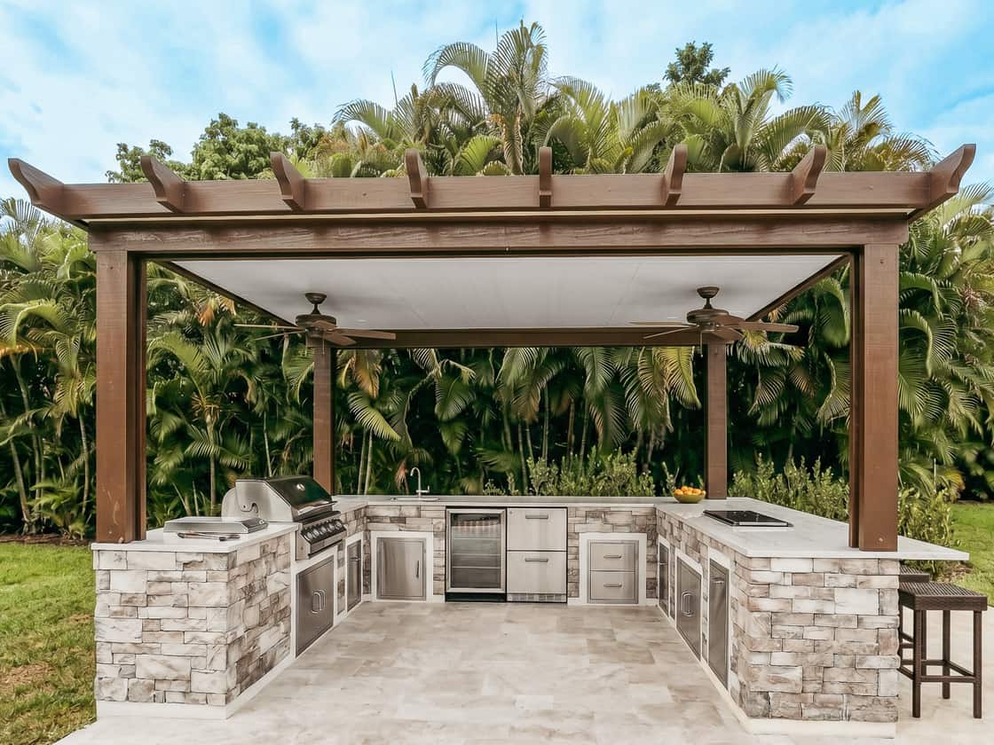 Pérgola de aluminio símil madera con toldo retráctil sobre una cocina exterior a medida en el sur de Florida